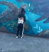 Child wearing Money Flow Tracksuit Set standing in front of a colorful ocean-themed mural.